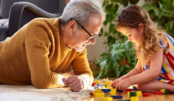 Older man playing blocks with young girl