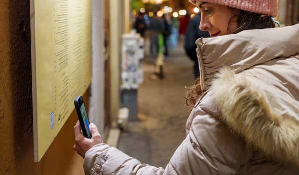 Woman scanning QR code outside restaurant