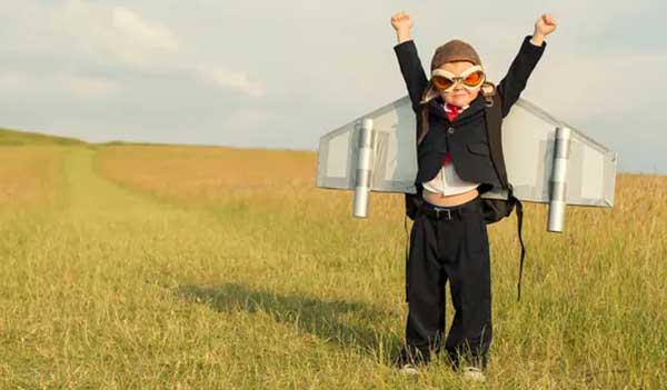 Child in field playing dressed as a rocket